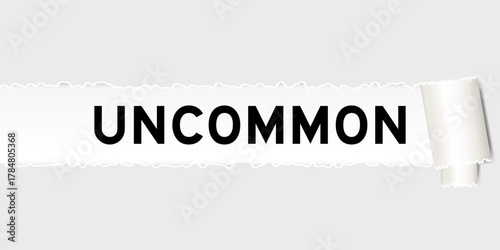 Ripped gray paper background that have word uncommon under torn part