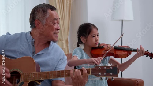 Asian family enjoys leisure time together at home, where a parent and child share a hobby playing violin. This moment reflects a lifestyle of love, childhood joy, and strong generational relationships