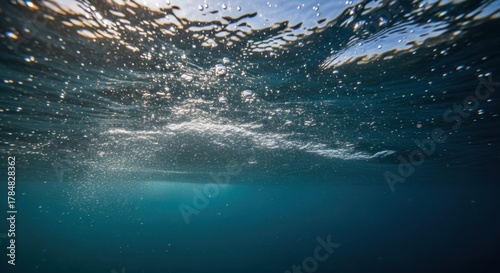 Fototapeta Naklejka Na Ścianę i Meble -  Deep sea perspective with sunlight filtering through the water surface. Abstract liquid texture with sparkling bubbles. Marine ecosystem and clean environment. Serene nature backdrop