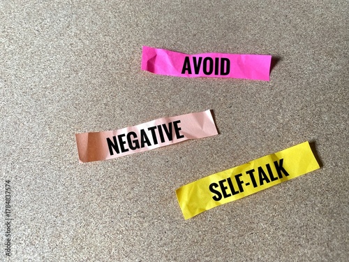 The words 'AVOID', 'NEGATIVE', and 'SELF-TALK' written on three separate pieces of brightly coloured crumpled paper.