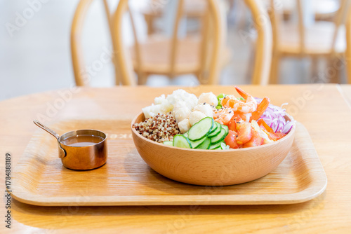 A gourmet poke bowl featuring scallops, shrimp, potato, cucumber, and quinoa rice, drizzled with parmesan cheese dressing and mustard vinaigrette. The dish presents a refreshing summer flavor with a b
