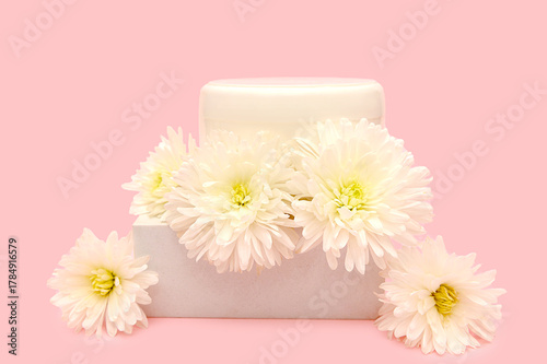 White plastic container on a podium with white flowers.
