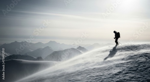 Lone skier silhouette on a windy mountain peak. Extreme winter sport adventure in a vast alpine landscape. Overcoming challenges and reaching the summit for success and freedom