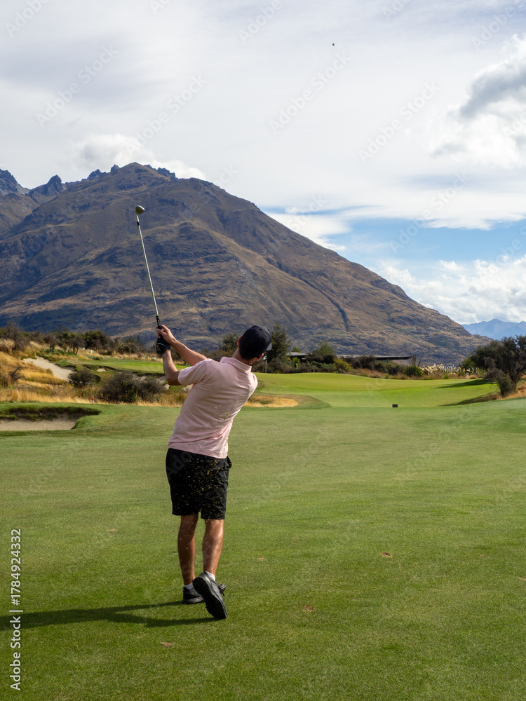 Obraz premium Golfer at Jack’s Point, Queenstown, New Zealand – Man in Pink Shirt Playing Golf with Scenic Mountain and Lake Wakatipu Views