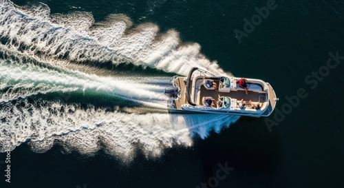 Aerial top down view of a luxury pontoon boat. Friends enjoying a summer vacation on the water. High speed motorboat creating a white wake on a deep blue lake. Recreational boating lifestyle