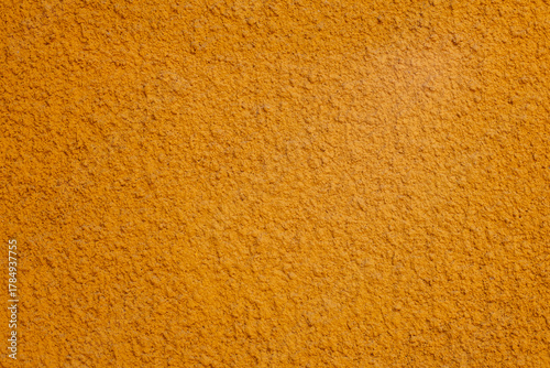 Turmeric powder texture on warm orange surface, a versatile spice for cooking and health