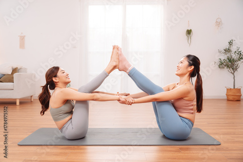 Wallpaper Mural Yoga pose with two Asian women practicing together on mat at home, partner stretch to improve balance, connection, flexibility, and wellness in a calm environment. Torontodigital.ca