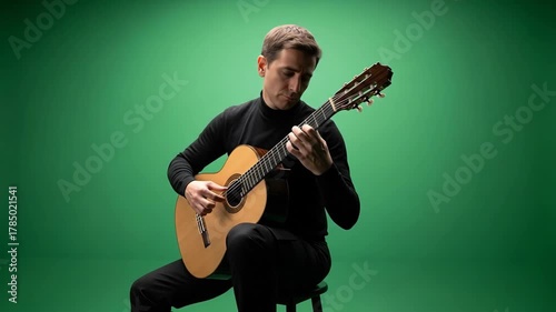 Vantage shot of man playing acoustic guitar in front of green screen