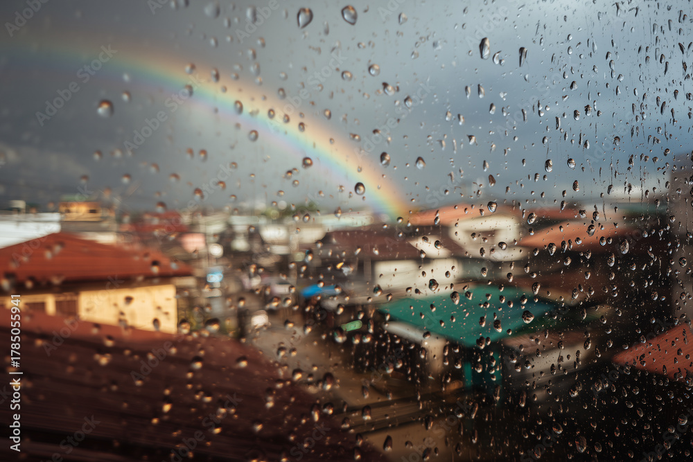 Naklejka premium Equatorial Monsoon City Balcony Photovoltaics With Raindrops And Faint Rainbow Over Rooftops, Focus-Pull Look, Afternoon Downpour
