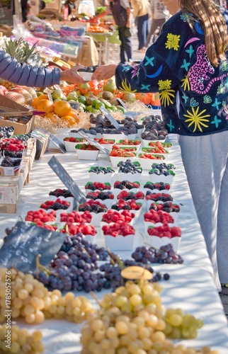 Clients en train de choisir des fruits et légumes frais sur un marché ensoleillé de Nice, côte d'azur
