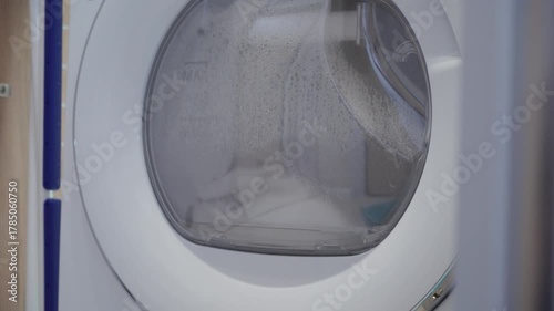 Laundry In Motion: Dryer Tumbles Wet Clothes with a Steady Whirring.