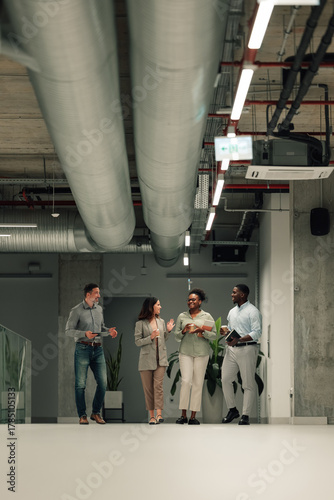 Diverse business people walking talking in modern office hallway