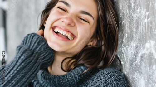 Young woman laughing in chunky knit sweater, cozy winter mood; joyful close-up suited for lifestyle and commercial.