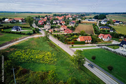 Fototapeta Naklejka Na Ścianę i Meble -  Aerial view of small village with houses, gardens and roads surrounded by farmland. Concept of rural life, housing and infrastructure