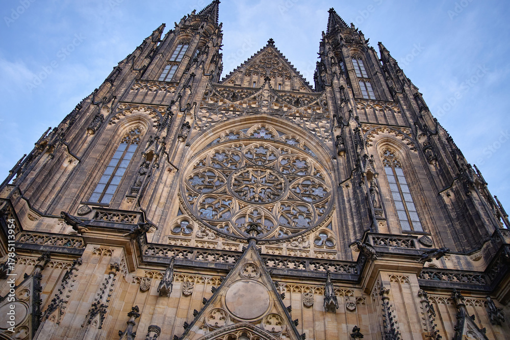 Fototapeta premium Detailed Gothic facade of St Vitus Cathedral with rose window and spires under blue sky in Prague, Czech Republic. Concept of religion, heritage and medieval architecture