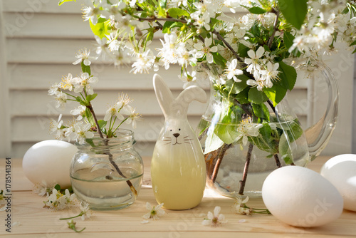 Easter still life with blossoming branches, decorative Easter bunny and eggs on the table