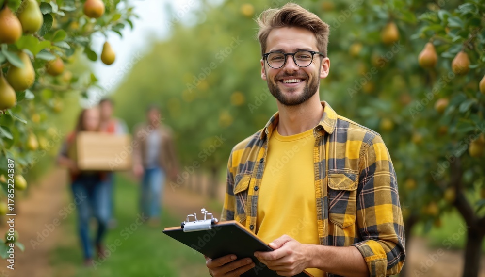 Obraz premium Man in glasses stands in pear orchard holding clipboard. Other people carry box with pears. Agriculture student checks fruit growing process. Young farmer works with crop. Healthy food production.