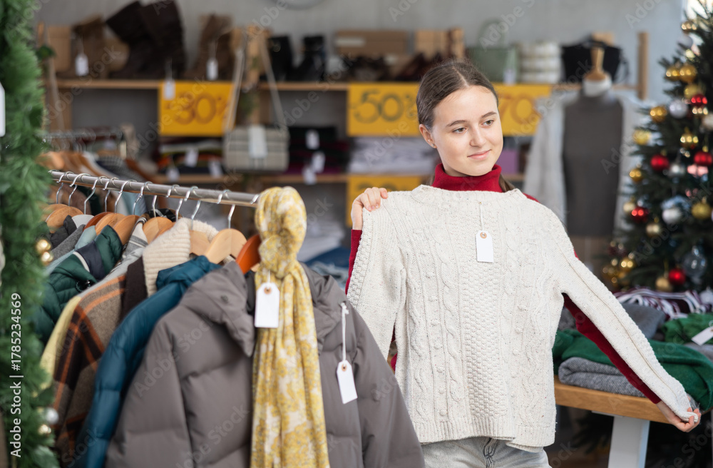 Fototapeta premium Teenage girl chooses a sweater in a fashion boutique.