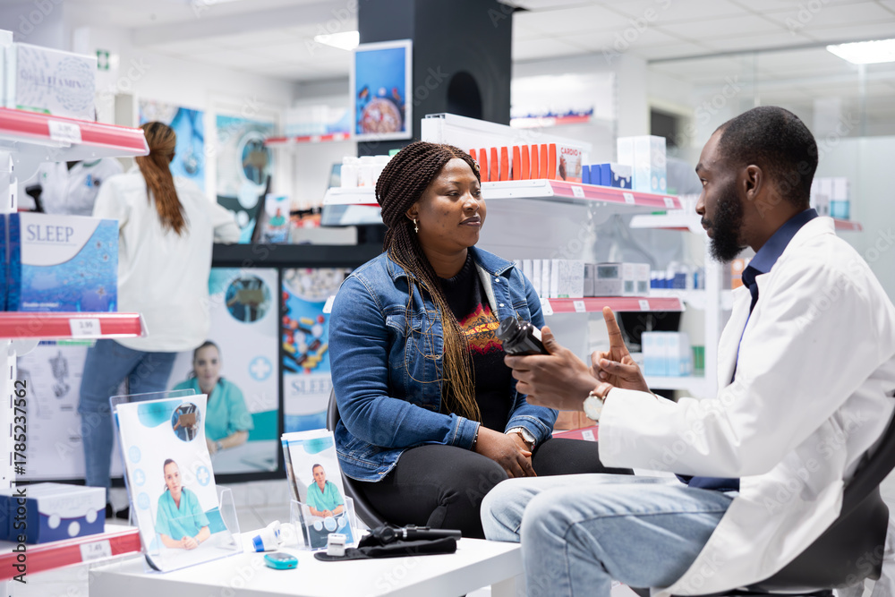 Fototapeta premium African american pharmacist consulting a client in the drugstore retail, assisting in giving professional advice and guidance for wellness. Apothecary service at pharmacy visit.