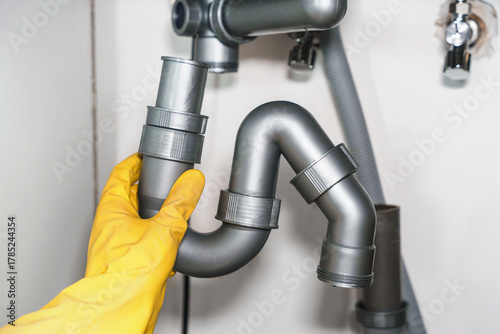 Gloved Hand Holding Sink Drain Pipe Section