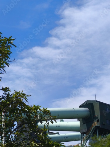 Industrial pipes and machinery structures against cloudy blue sky