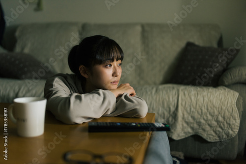 電気を消してテレビを観る若い女性