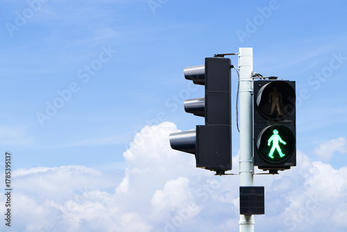 Traffic lights with green or red light lit hanging on steel pole with blue sky cloud white is background. Safety with people to travel. Sign or symbol icon pedestrians not allowed crossing road. 