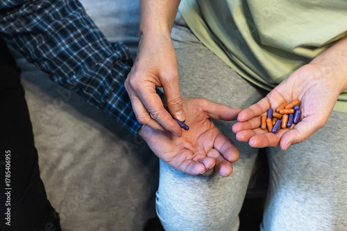 Hands exchanging medicine during a health check in a cozy living room setting