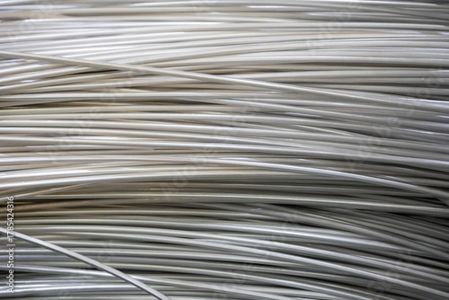 Tableau sur toile Close-up of coiled aluminum wires, highlighting their smooth surface and layered overlapping pattern, captured in soft lighting