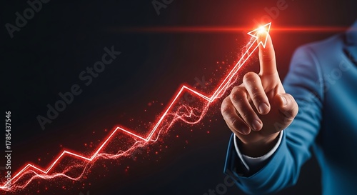 Business man pointing at glowing red arrow graph going up on dark background