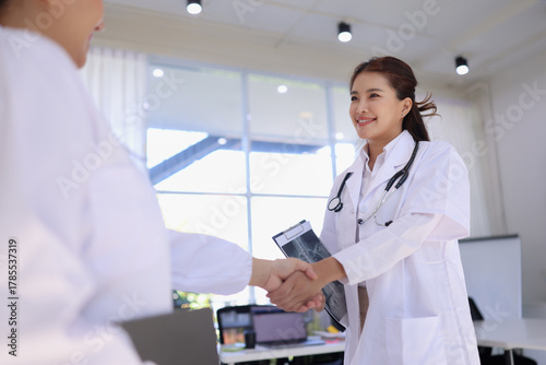 Two professional female doctor shaking hands in clinic. Medical and Healthcare concept. 