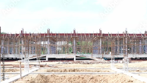 Construction site with concrete foundation, steel scaffolding, wooden framework, and unfinished building structure bright daylight, showing progress and development urban area, building construction