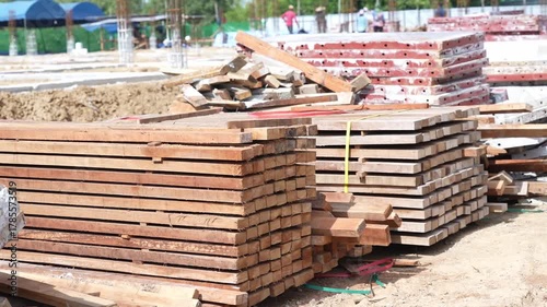 Stacked Wood Plank Construction Material at Outdoor Building Site with Sunlight, Organized Lumber Stack, Industrial Preparation for Structure, Brown Timber, Horizontal Lines, Summer Work in Progress