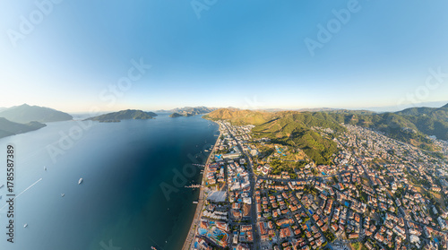 Fototapeta Naklejka Na Ścianę i Meble -  Marmaris, Turkey. Panoramic aerial view of coastline with beaches and hotels, city and forested mountains in morning sunlight. Coastal urban landscape. Aerial view.