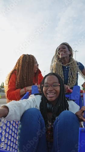 Three young happy women enjoying a shopping cart ride