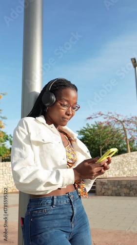 Young woman listening to music while using a smartphone outdoors