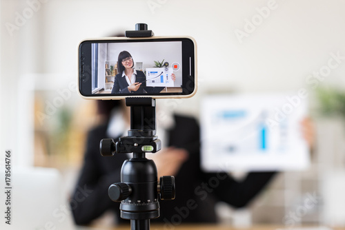 Caucasian young adult woman sitting at table holding presentation while recording blog. Concept of business, communication, and content creation.