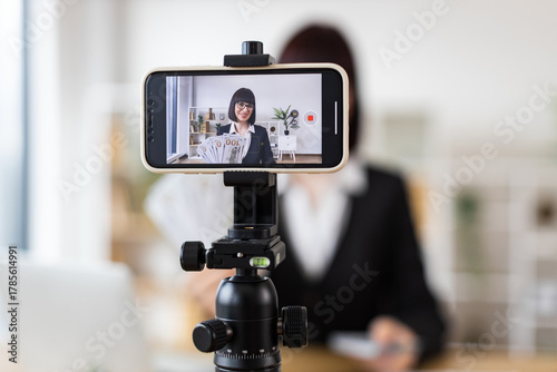 Caucasian woman recording financial literacy video showcasing cash, providing investment tips, income insights