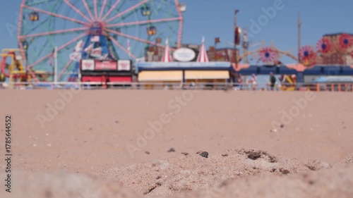 Coney Island sandy beach in Brooklyn, New York, United States. Boardwalk near retro luna park. Ferris wheel in american amusement park on ocean coast. Waterfront summer holiday promenade in NYC, USA.