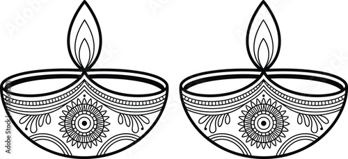 Two black and white ornate diya lamps with flames oil lamp