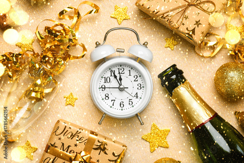 Top view of white alarm clock with bottle of champagne,crystal glasses,golden christmas balls and Christmas gifts.New years eve celebration concept background