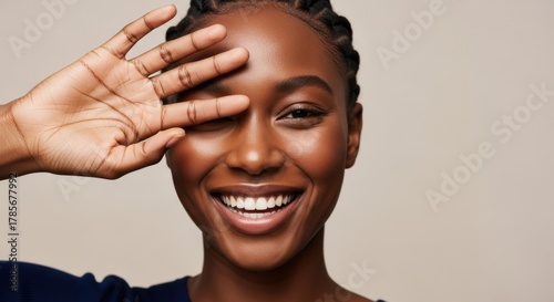 Happy woman smiling with hand over eye, radiating joy and confidence in portrait