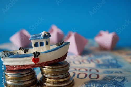 A toy boat and a stack of coins on a blue background.