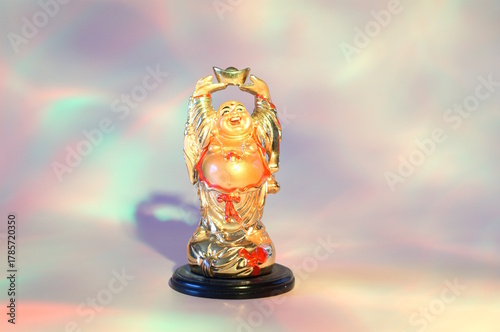 A statue of a smiling Buddha on a pink rainbow background.