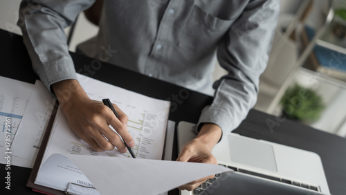 Asian business man holding paper document calculating tax insurance managing budget