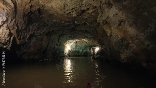 Interior view of a limestone cave in Tràng An, Ninh Binh, featuring still water and natural rock formations.
