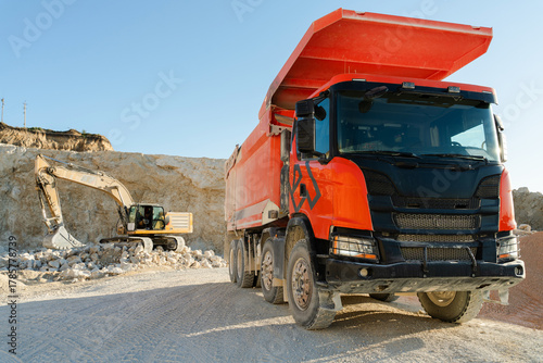 Slika na platnu Large orange dump truck standing on quarry ground, used for hauling rocks and co