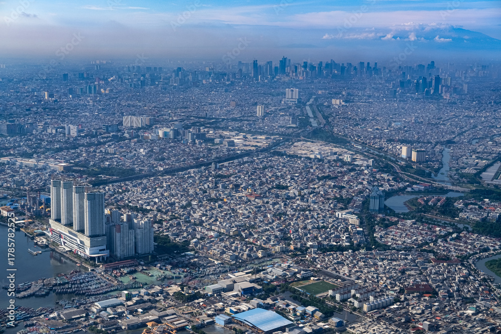 Obraz premium Dense northern Jakarta coastline seen from above, showing rapid urban expansion along the shore as rising sea levels and climate risks threaten low lying districts and future city resilience.