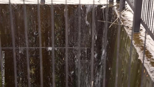 Water flowing over spillway dam into canal through a metal grate