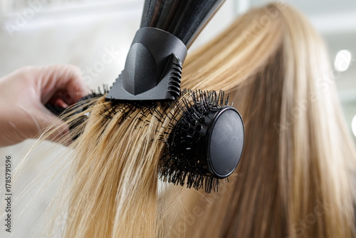Concentrator nozzle and round brush blowout on long blonde hair in salon